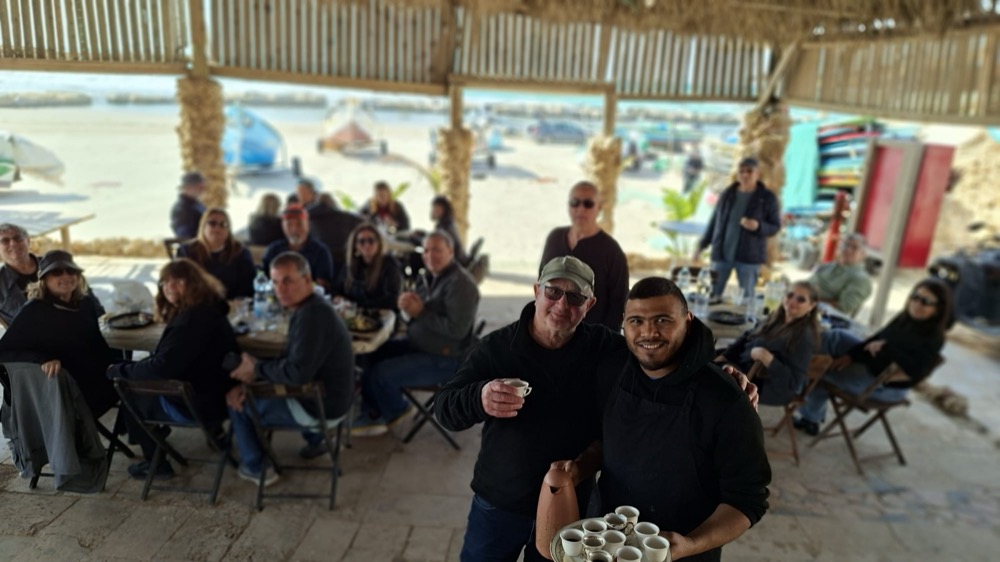 שולחן ערוך לארוחה מול סירות הדייגים בלב ים